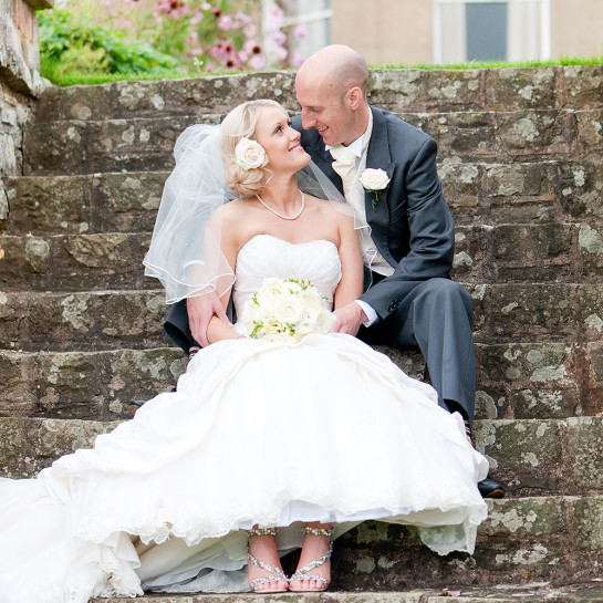 A wedding couple on some garden steps at Burton Court.
