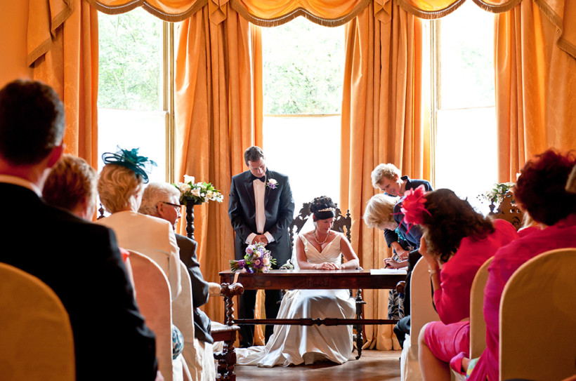 A wedding couple signing the registry during a Civil Ceremony being held in the Regency Room.