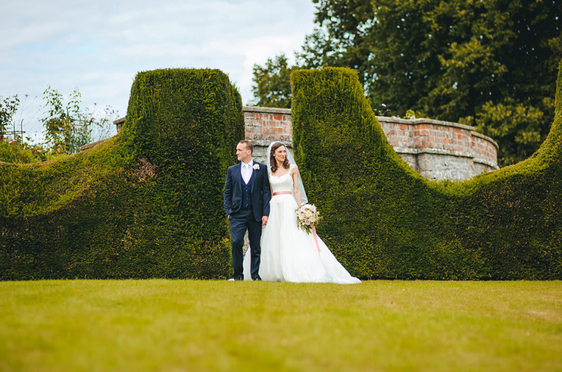 A wedding couple in the trimmed topiary garden in the gardens of Burton Court.
